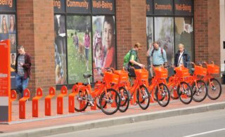 Passersby check out the Biketown bikes in the station at SW 5th and Oak.(Photo: J. Maus/BikePortland)