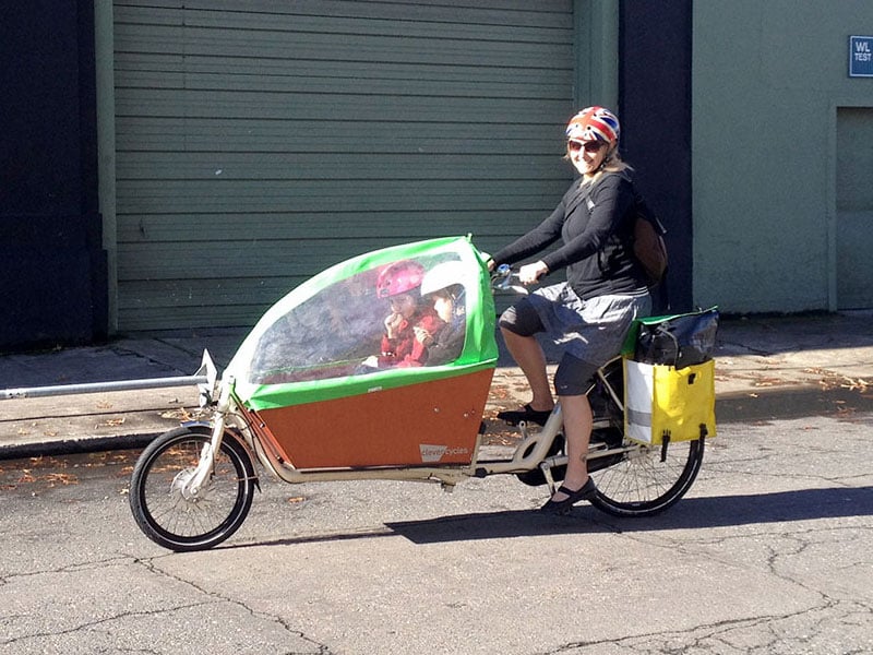 A bakfiets with canopy keeps passengers comfy.