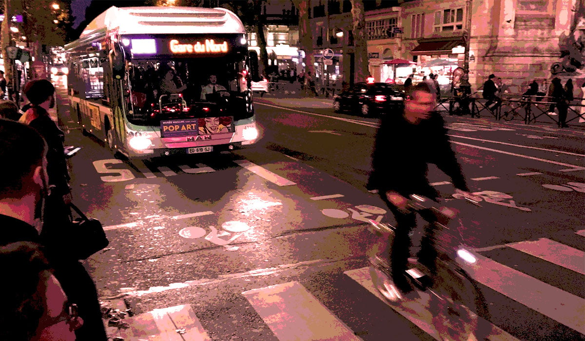 Night shot of pedestrians crossing road full of mopeds in busy