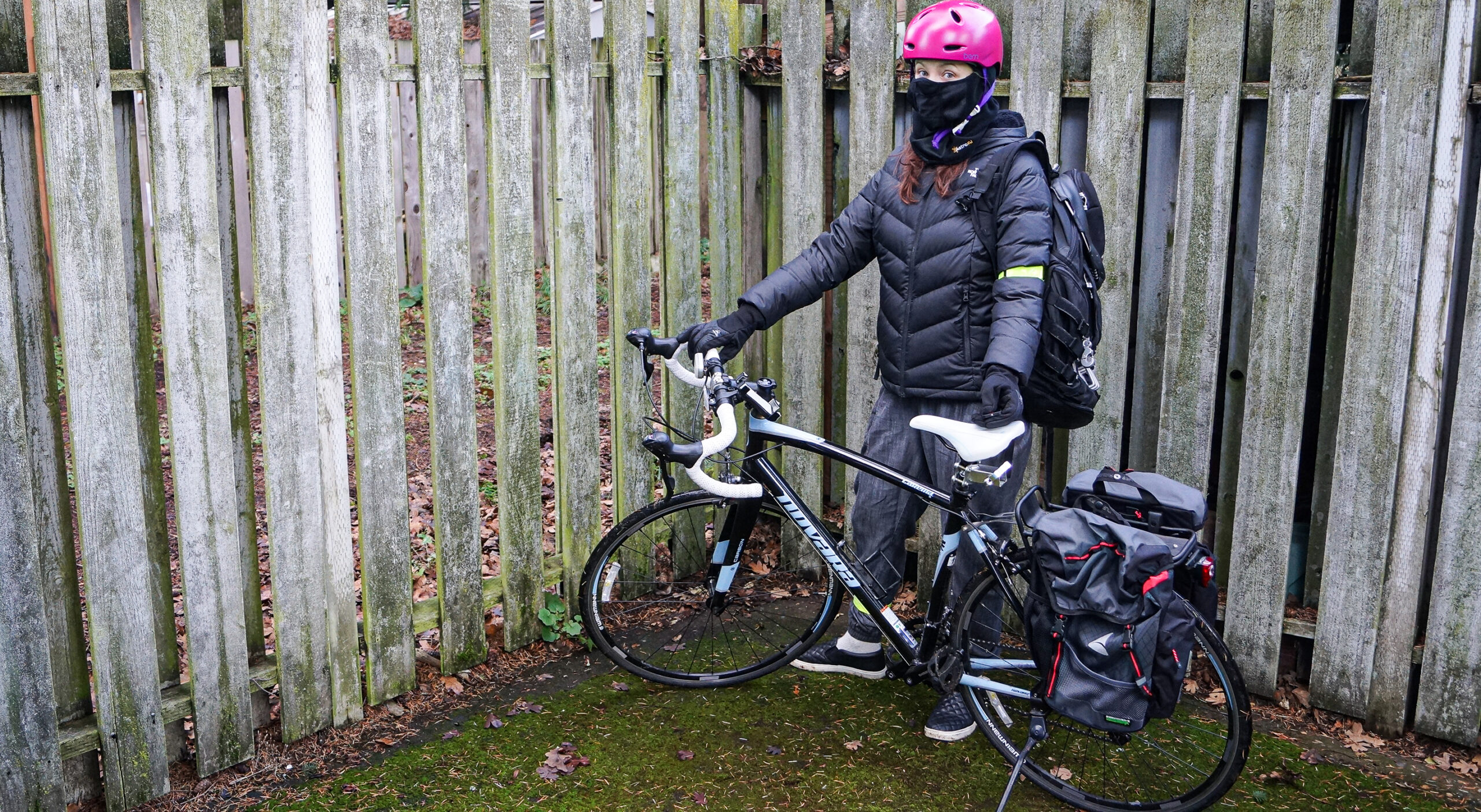 female cyclist standing in wet weather gear with bike