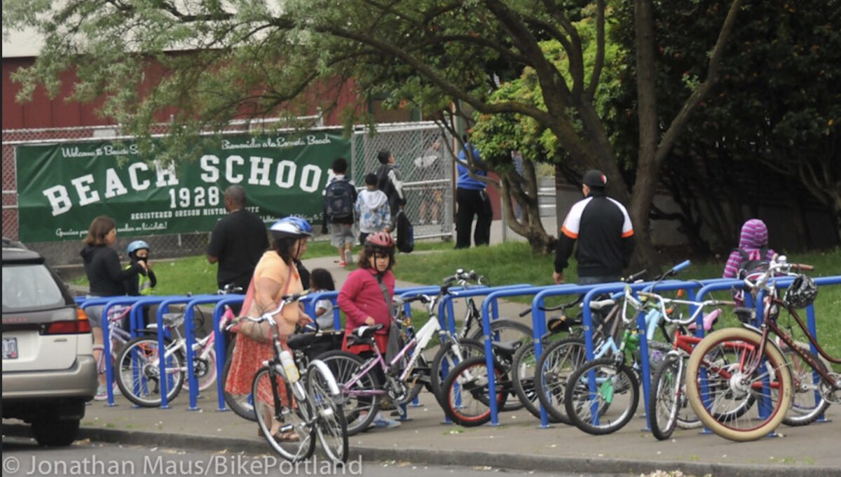 Kids parking bicycles at racks in front of a school.