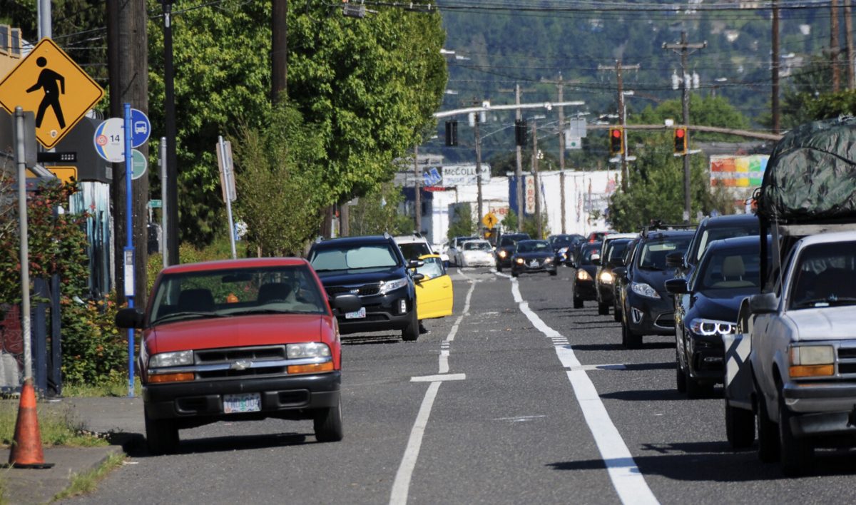 An empty bike lane on a multi-lane street full of drivers and cars.