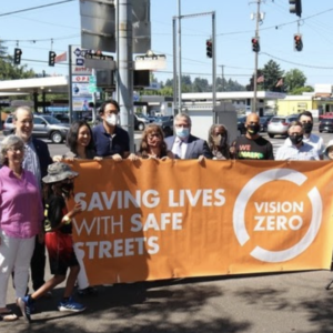 Electeds, advocates, and agency leaders hold a Vision Zero banner on the corner of 82nd and Glisan Tuesday. (Photo: PBOT)