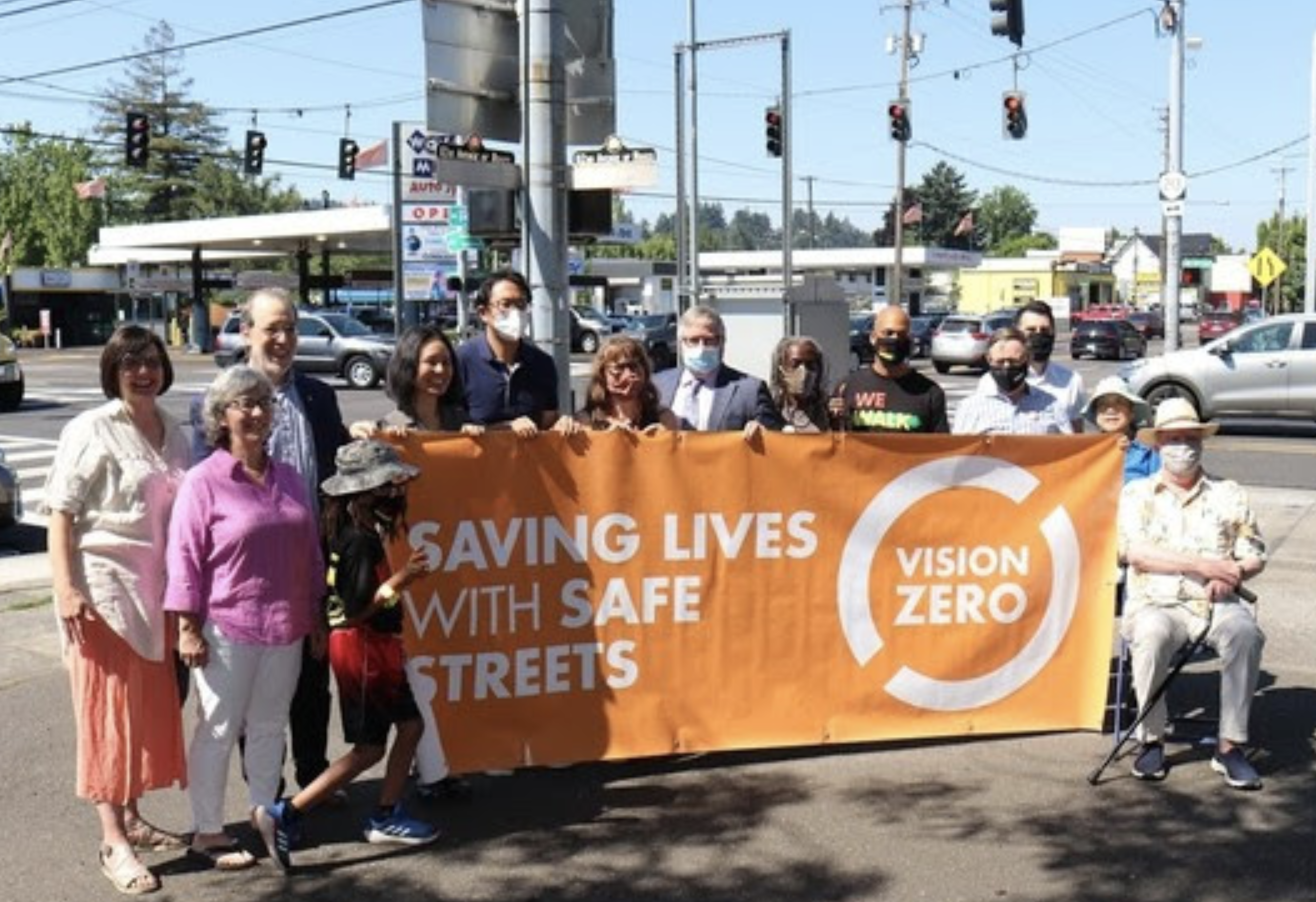 Electeds, advocates, and agency leaders hold a Vision Zero banner on the corner of 82nd and Glisan Tuesday. (Photo: PBOT)