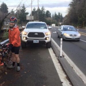 man with a bike walks around truck parked in bike lane