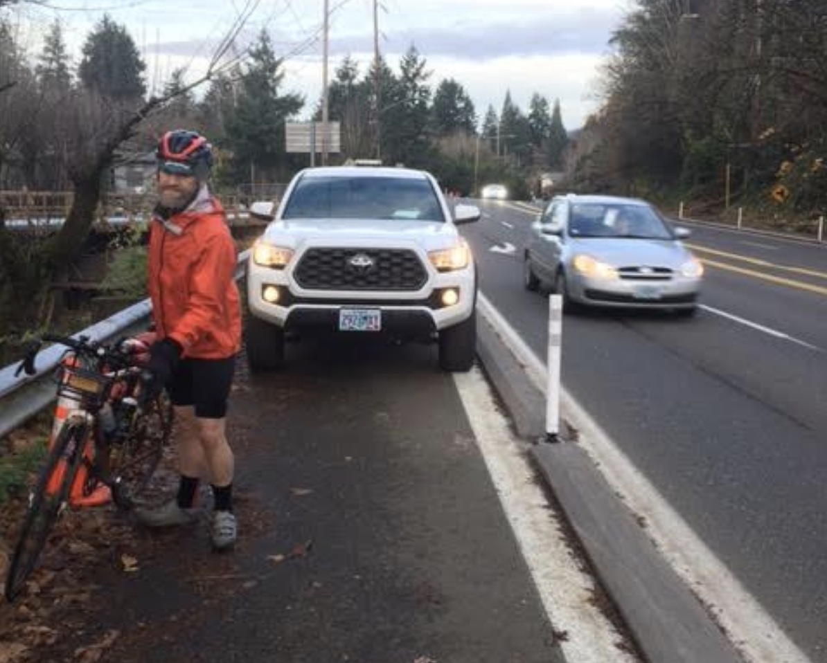 man with a bike walks around truck parked in bike lane