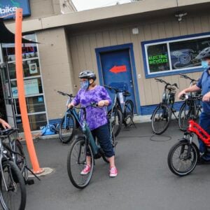 people outside a bike shop test-riding bikes