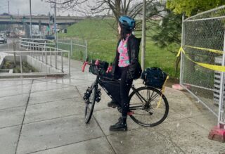 Woman straddling a bike on the sidewalk with light snow falling