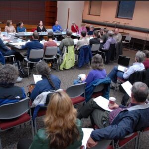 people sitting in chairs around a table in a conference room