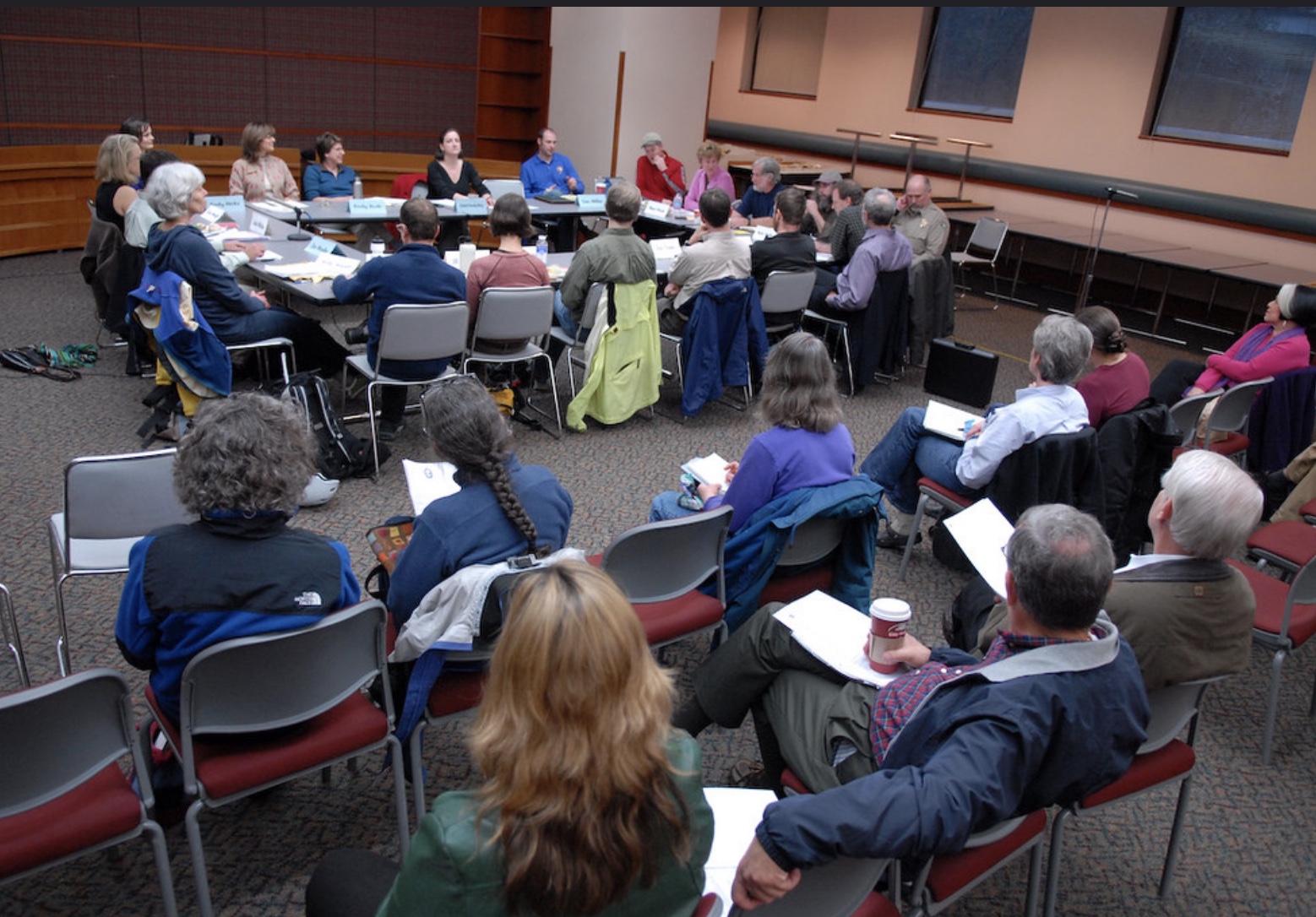 people sitting in chairs around a table in a conference room