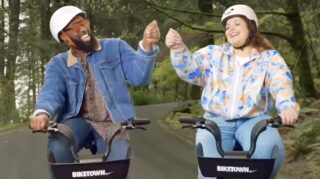 two people biking in the woods giving each other a fist bump and smiling.