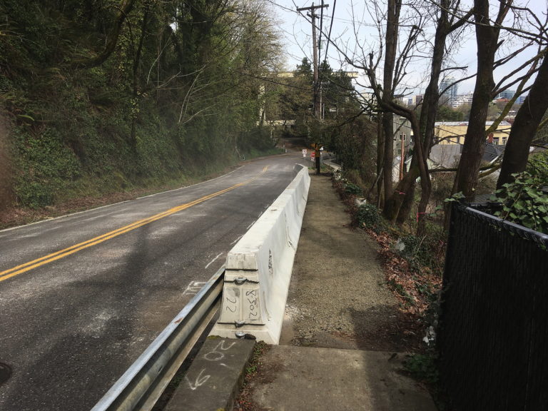 Street and side path separated by white concrete wall