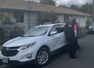 People standing on the street next to a white City of Portland vehicle.