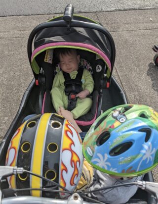 Child seat in a front cargo box of a bicycle with a baby inside.