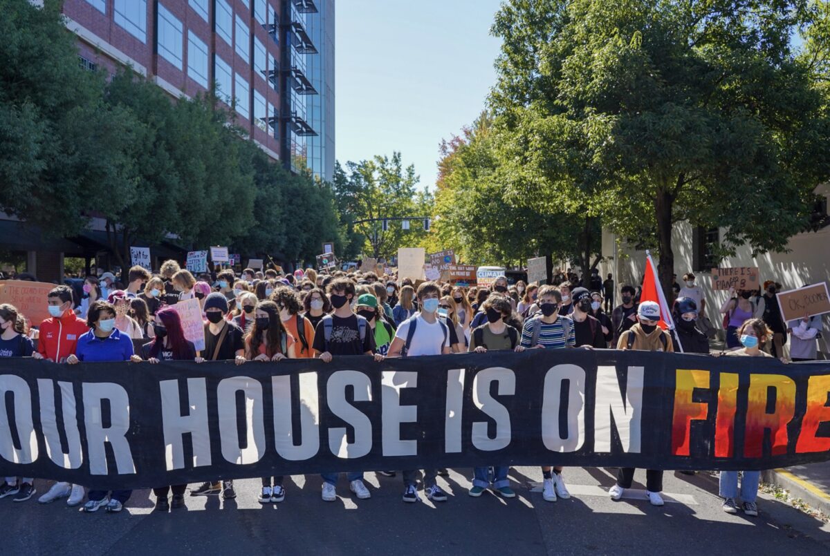 Group of protestors marching in the street with a banner that reads "Our house is on fire".