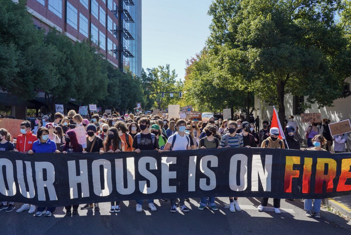 Group of protestors marching in the street with a banner that reads 