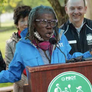 Jo Ann Hardesty wearing a blue jacket speaking at a lectern during a PBOT event.