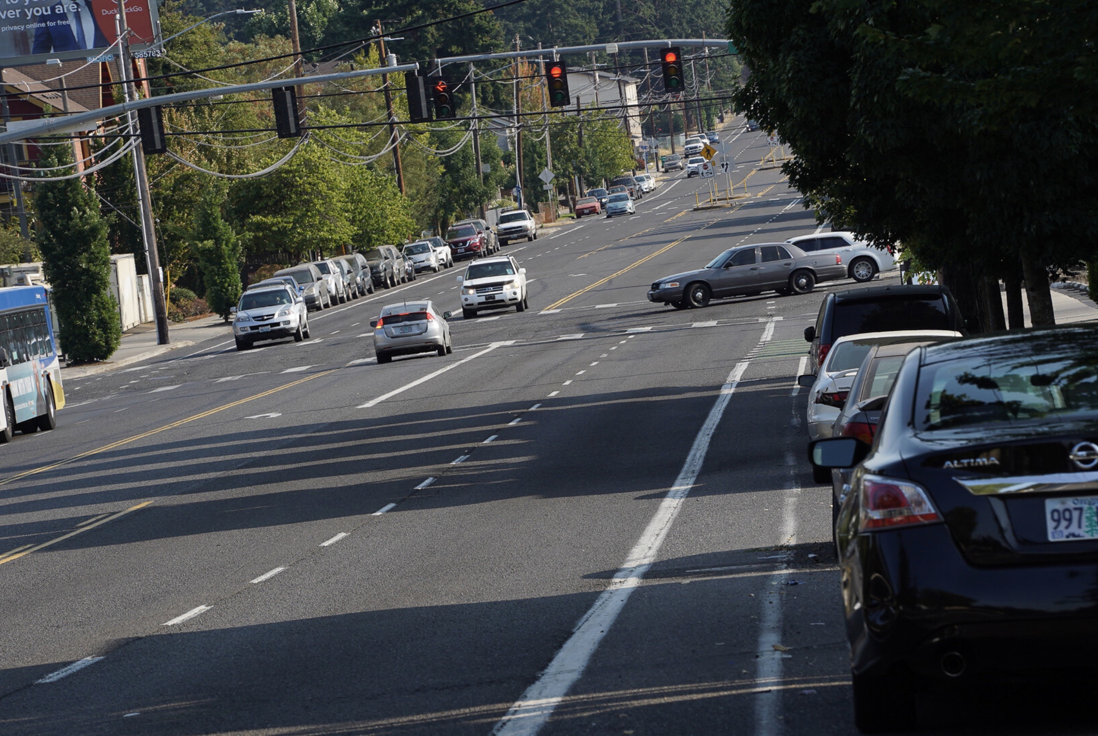 Wide arterial street with parked cars in one lane.