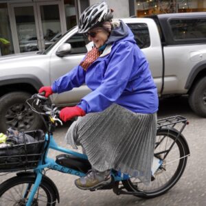 Person with a dress riding a bike on the street.