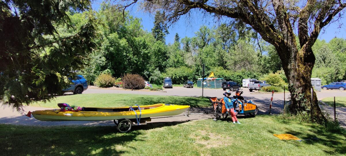 Kayak towed behind a bike in a park.