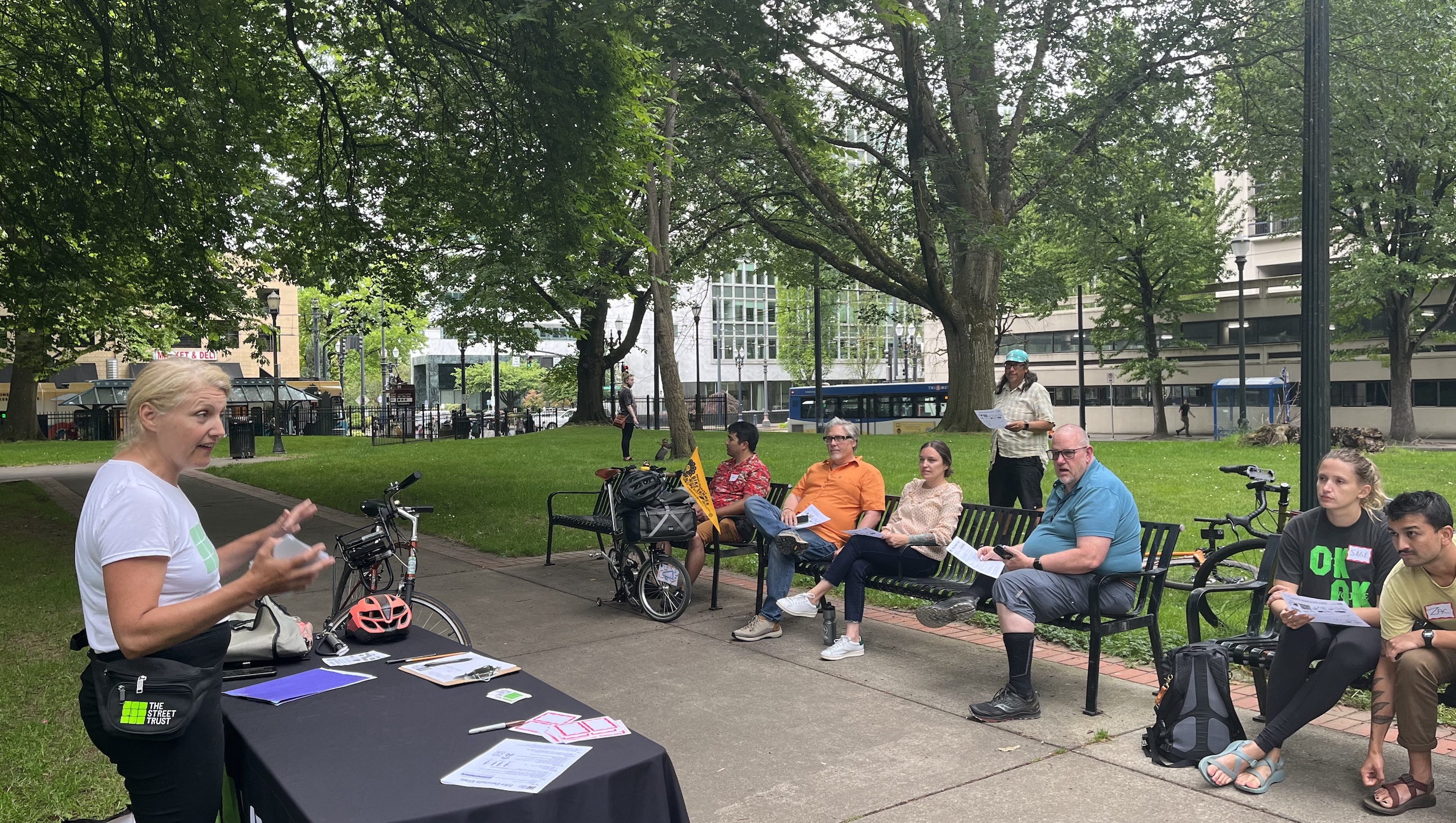 people sitting in a park listening to someone speak